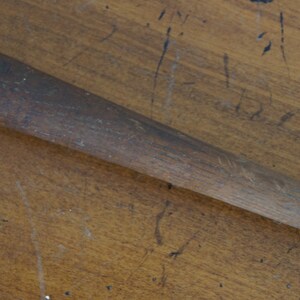 May include: A close-up of a wooden baseball bat with a worn, brown finish.
