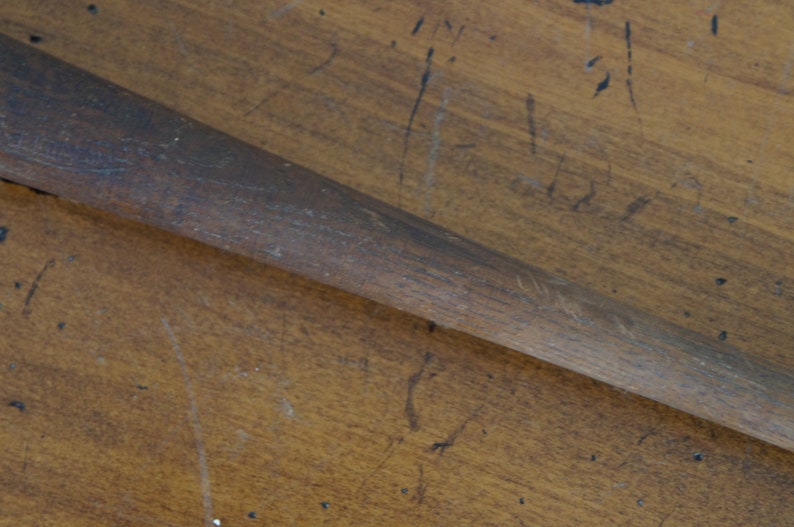 May include: A close-up of a wooden baseball bat with a worn, brown finish.