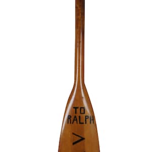 May include: A wooden paddle with the text "TO RALPH AXA FROM GIL" written on it.