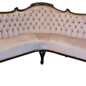 Peut inclure: Un grand canap&eacute; en velours beige capitonn&eacute;, incurv&eacute;, avec une structure en bois fonc&eacute; et des pieds sculpt&eacute;s.