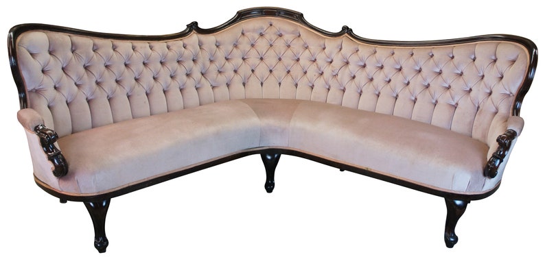 Peut inclure: Un grand canap&eacute; en velours beige capitonn&eacute;, incurv&eacute;, avec une structure en bois fonc&eacute; et des pieds sculpt&eacute;s.
