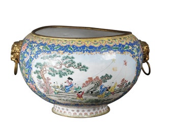 May include: A large, oval-shaped, blue and white porcelain planter with gold accents and lion head handles. The planter features a scene of children playing with kites in a garden setting.
