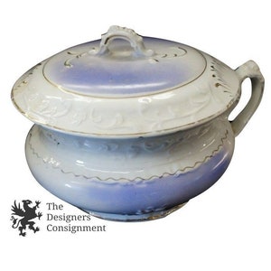 May include: A white porcelain chamber pot with a blue and white glaze and gold trim. The pot has a lid with a handle and a decorative floral design.