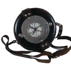 May include: A black leather timekeeping device with a silver face and a strap. The face has a clock with black hands and white numbers.