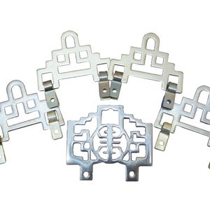 May include: A collection of silver-colored metal brackets with intricate geometric cutouts. The brackets have a decorative design and are connected with small metal hinges. The brackets are arranged on a white background.