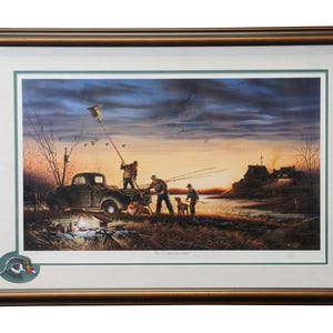 May include: Framed print of a painting depicting a group of hunters standing near a vintage pickup truck in a field at sunset. The hunters are wearing camouflage clothing and holding rifles. A dog is standing near the truck. The painting is titled "The Commemorative".