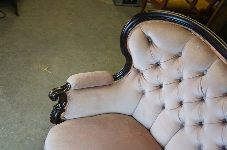 Peut inclure: Un canap&eacute; vintage capitonn&eacute; avec un rev&ecirc;tement en velours rose clair et une structure en bois fonc&eacute;. Le canap&eacute; a un dossier incurv&eacute; et des accoudoirs roul&eacute;s.