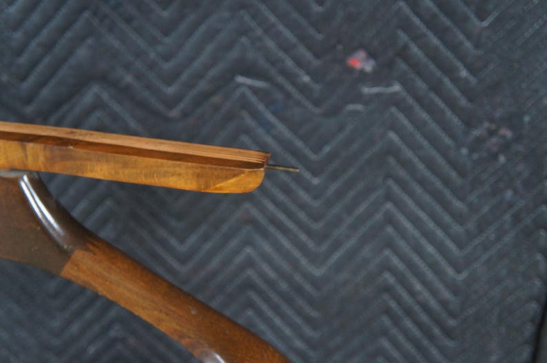 May include: Close-up of a wooden clothes hanger with a dark finish. The hanger has a curved design with a metal hook and a wooden bar for hanging garments. The wood grain is visible.