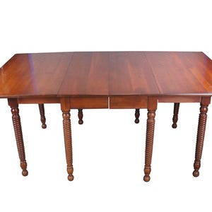 May include: A rectangular wooden dining table with a rich brown finish. The table features a drop-leaf design and ornate, carved legs. The table is approximately 60 inches long when fully extended.