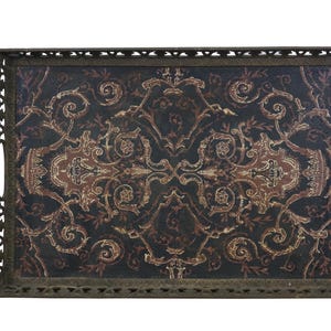 May include: Rectangular serving tray with a dark background and an ornate, repeating pattern in shades of brown and gold. The tray has a decorative, openwork metal frame with handles, suitable for serving food or displaying decorative items.