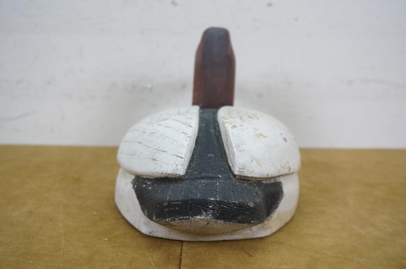 May include: A vintage wooden duck decoy, hand-painted with a white body, black accents, and a brown neck. The decoy has a weathered appearance, suggesting it's an antique or a rustic decorative item.