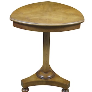 May include: A light brown, three-legged side table with a semi-circular top. The table has a single central support and decorative feet. The table is made of wood and has a varnished finish.