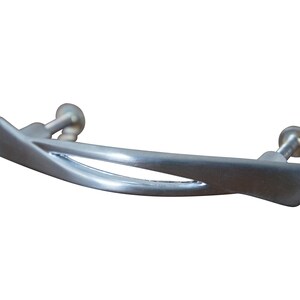 May include: A silver-toned cabinet pull with a modern, abstract design. The pull has a curved shape with a cut-out in the center.