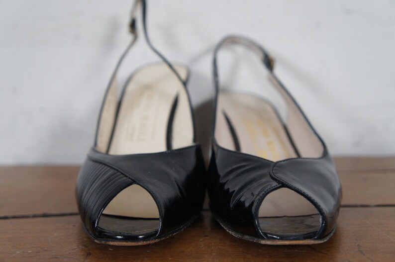 May include: A pair of black peep-toe heeled shoes with slingback straps.
