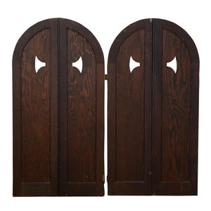 May include: A pair of dark brown wooden doors with an arched top and a decorative cutout. The doors are hinged together and feature a wood grain pattern. The cutout is shaped like a stylized arrow.