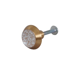 May include: A white and gold cabinet knob with a speckled pattern. The knob has a round base and a metal screw.