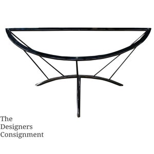 May include: Black metal table base with a curved top and three legs. The base is designed in a modern style.