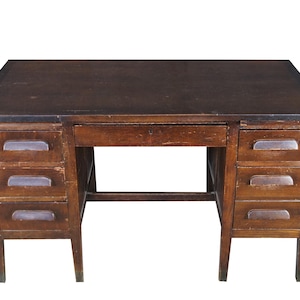 May include: A rectangular wooden desk with a dark brown finish, featuring a flat top surface, a central drawer with a keyhole, and two side pedestals each containing three stacked drawers with horizontal metal pulls and visible wood grain.