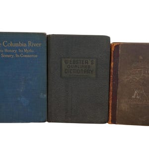 May include: Three vintage hardcover books. The book on the left is blue with gold lettering that reads "The Columbia River Its History: Its Myths. Its Scenery, Its Commerce". The middle book is black with gold lettering that reads "Webster's Qualified Dictionary". The book on the right is brown with gold lettering and a design on the cover.