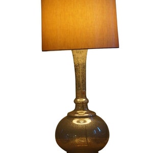 May include: A gold-toned table lamp with a round, textured glass base and a brown fabric lampshade.