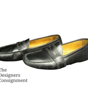 May include: A pair of black leather loafers with a stitched design. The loafers have a brown leather lining and a rounded toe.