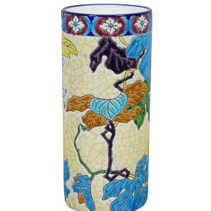 May include: A cylindrical ceramic vase with a cream-colored background and a crackle glaze. The vase is decorated with colorful leaves in shades of blue, orange, and green. The top rim features a blue band with floral patterns.