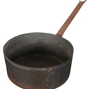 May include: A vintage copper pot with a long handle. The pot has a dark brown patina and is slightly dented.