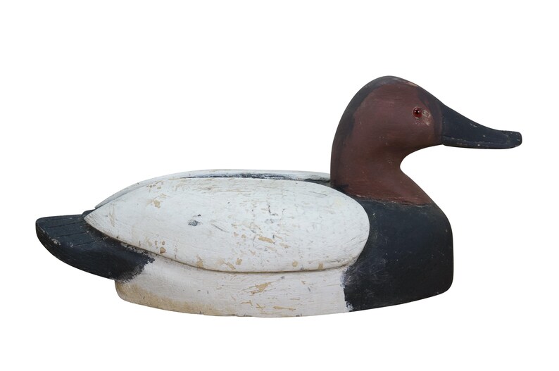 May include: A wooden duck decoy with a white body, black tail and chest, and a brown head and beak. The decoy has a weathered appearance, suggesting it is vintage or antique. This decorative item is likely used for home decor or as a collectible.