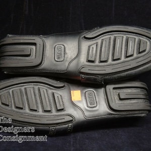 May include: A pair of black leather loafers with a textured rubber sole. The loafers have the word "Polo" embossed on the side.