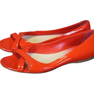 May include: A pair of bright red, open-toe, heeled shoes with a criss-cross strap design.