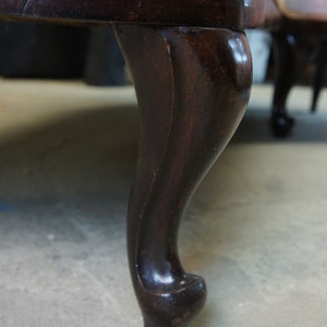 Peut inclure: Gros plan sur une patte de canap&eacute; en bois brun fonc&eacute; avec un design cabriole. La patte est incurv&eacute;e et poss&egrave;de un pied d&eacute;coratif.