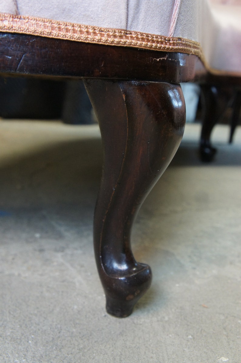 Peut inclure: Gros plan sur une patte de canap&eacute; en bois brun fonc&eacute; avec un design cabriole. La patte est incurv&eacute;e et poss&egrave;de un pied d&eacute;coratif.