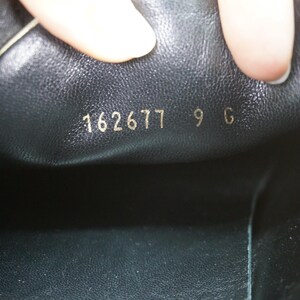 May include: Close-up of the inside of a black shoe. Gold lettering reads "162677 9 G". The shoe's interior is black leather. The image is well-lit, highlighting the details of the shoe's construction.
