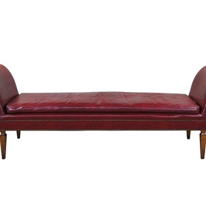 May include: A red leather bench with a tufted seat and wooden legs.