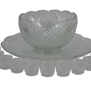May include: A clear glass punch bowl set with a large bowl, a matching plate, and 16 small cups. The bowl and plate have a diamond pattern and a scalloped edge.