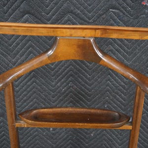 May include: A wooden valet stand with a built-in clothes hanger and a small tray. A silver-colored shoehorn is attached to the side. The stand is made of dark-stained wood and has a classic design.