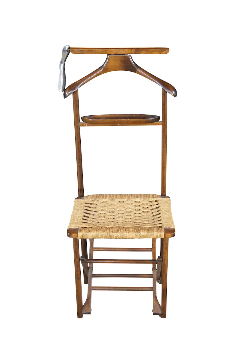 May include: A wooden valet chair with a woven seat and a built-in hanger. The chair has a small shelf and a metal hook. The chair is made of wood and has a natural finish.