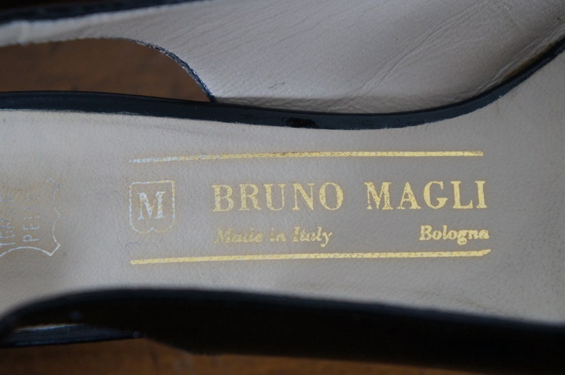 May include: Close-up of the inside of a black leather shoe with a gold label that reads "BRUNO MAGLI Made in Italy Bologna".