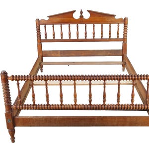 May include: A wooden bed frame featuring a tall headboard with a decorative top rail and vertical spindles. The footboard is lower, matching the headboard with a series of turned, spool-like spindles and sturdy corner posts with finials.
