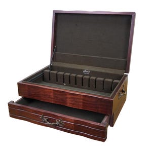 May include: A wooden silverware chest with a dark brown finish. The top is open, revealing a felt-lined interior with slots for utensils. A drawer is partially open at the bottom. The chest has decorative hardware.