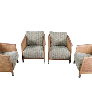 May include: Four armchairs with woven rattan frames and patterned cushions. The chairs have wooden armrests and legs. The cushions have a green and beige pattern. The chairs are arranged against a white background.