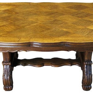 May include: A dark wood dining table with a parquet top and carved legs. The table has a scalloped edge and a stretcher.
