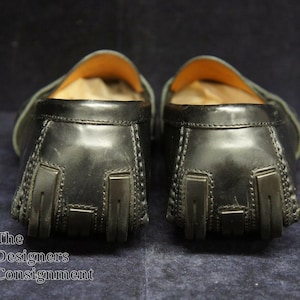 May include: A pair of black leather loafers with a textured design on the back. The loafers have a brown leather lining and a rubber sole.