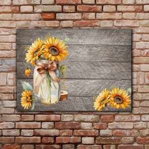 May include: A watercolour painting of sunflowers in a mason jar with a brown ribbon tied around the jar. The jar is sitting on a grey wooden background.