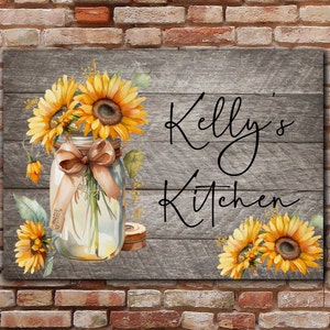 May include: A rustic wooden sign with the text "Kelly's Kitchen" in black script. The sign is decorated with a mason jar filled with sunflowers and a brown ribbon.