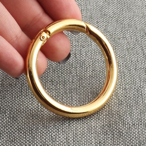 Peut inclure: Un anneau en métal doré avec une ouverture à charnière. L'anneau est lisse et brillant.