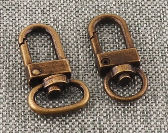 Puede incluir: Dos cierres giratorios de metal de color dorado antiguo con una puerta de resorte. Los cierres tienen un anillo en D en un extremo y un gancho en el otro.