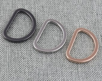 May include: Three D-shaped metal rings in black, silver, and rose gold.