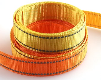 May include: Two rolls of yellow and orange webbing with black stitching. The webbing is woven with a textured pattern.