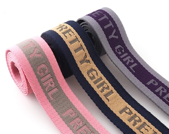 May include: Three different colored woven fabric straps with the text "Pretty Girl" printed on them. The straps are pink, navy blue, and gray.